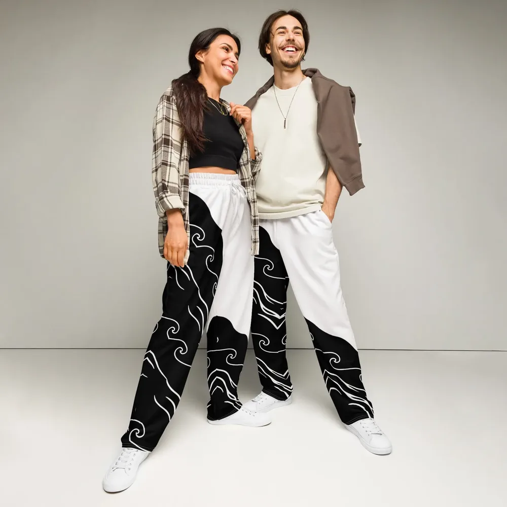Two people wear the Waveform Wide Leg Joggers, black and white with a wave print, in a pale studio.